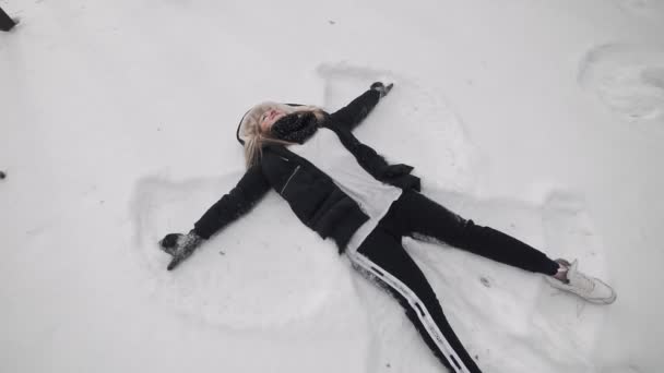 Kameran Flyttar Från Kvinna Som Ligger Snö Och Gör Snow — Stockvideo