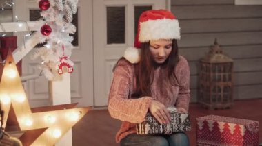 Noel şapka sarma hediyeler hediyeler çekici kız. Slo-mo. Xmas konseptinde noel için hazırlanıyor pullover genç esmer kız