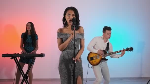 Hermosa Mujer Vestido Cantando Canción Micrófono Con Banda Fondo Colorido — Vídeo de stock