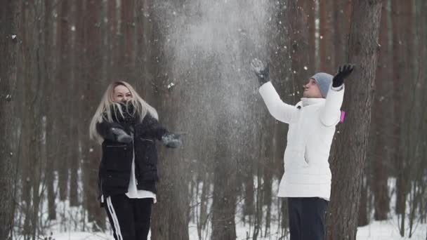 Щасливі молоді люди кидають сніг над головою. Щаслива пара розважається зі снігом — стокове відео