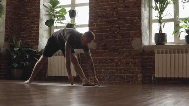 Man Practice avancerad yoga pose i Studio med tegelvägg och stora fönster — Stockvideo
