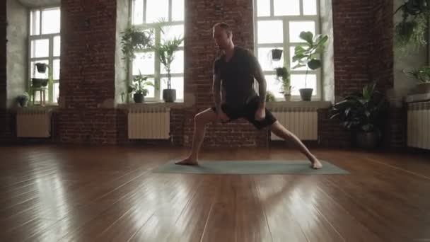 Man practice warrior yoga pose in studio. Sporty man in shorts doing yoga — Stock Video