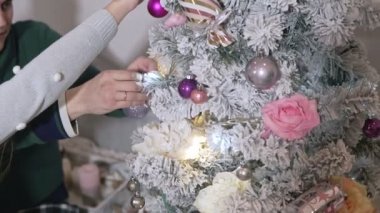 Noel topları ile Noel ağacı dekorasyon genç aile. Erkek ve kadın yavaş çekimde ağacı süslerler. Yakın çekim