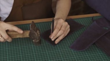 Deri işçisi deride delikler açar. Deri cüzdan el yapımı üretim süreci. Master yakın atölyede cüzdan yapar.