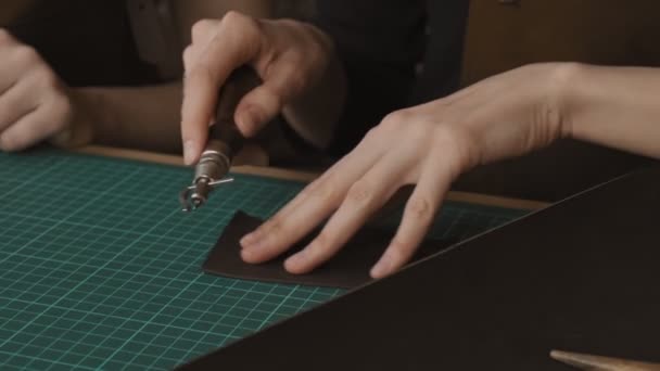 스키너는 도구를 구멍에 그립니다 마스터는 워크샵에서 지갑을 만든다 슬로우 모션으로 — 비디오