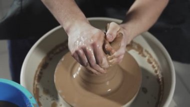 Potter çömlekçi tekerleğinde sürahi oluşturur. Ellerin yakın çekim yavaşça kilden doğru şekilli el yapımı oluşturmak