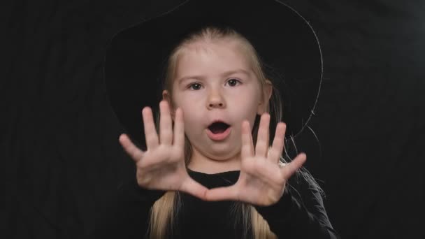 小漂亮的女孩女巫在黑色礼服和帽子在黑暗的背景尖叫 万圣节概念 特写肖像 — 图库视频影像