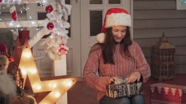 Noel şapkalı genç kadın hediyeleri paketliyor. Pullover genç esmer kız kopya alanı ile yavaş çekimde noel için hazırlanıyor. Xmas kavramı