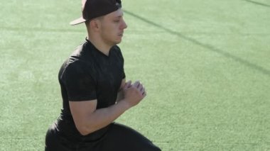 Stadyumda bacaklarını uzatan genç adam. Atlet adam güneşli sabah egzersiz öncesi ısınma. Genç sportif adamın yakın çekim idman öncesi ısınma yapar.
