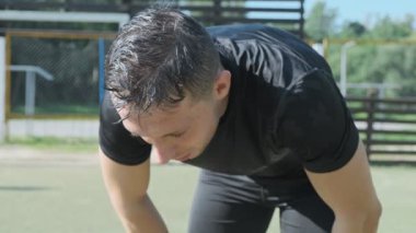 Yorgun adam başını kaldırıp kameraya bakar. Kapalı çekim yorgun yüz ve terli adam dışarıda çalışmayı bitirdi..