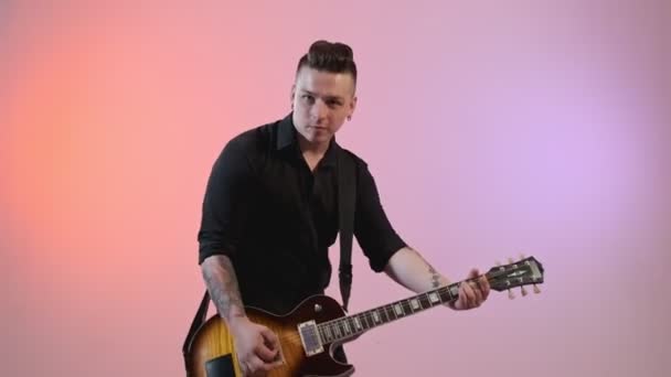 Gutaussehender Tätowierter Rockmusiker Der Sologitarre Spielt Und Die Kamera Schaut — Stockvideo