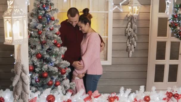 年轻幸福的母亲 父亲和小女儿的家庭在拉聚机装饰圣诞节和新年树一起在门廊慢动作 — 图库视频影像