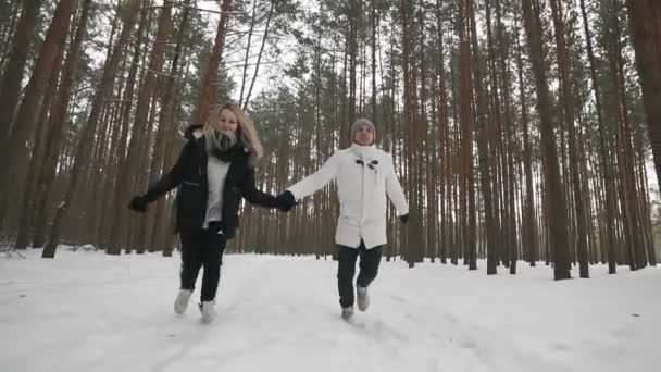 若いカップルが走り 屋外でスローモーションで松林で楽しんでいる冬のショット 雪の天気 — ストック動画