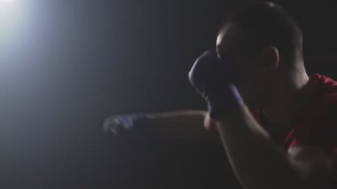 Muay Tay savaşçı dumanlı Studio'da Delme. Ağır çekimde düşük ışık salonunda eğitim kick boks şampiyonu. Siluet koyu arka plan üzerinde