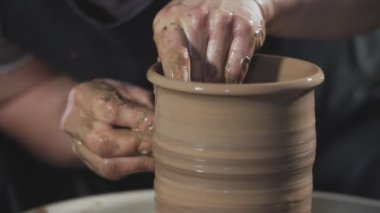 Çömlekçi tekerleğiüzerinde kil ile çalışan çömlekçi yakın. Adam yavaşça yavaş harekette kilden sürahi oluşturmak.
