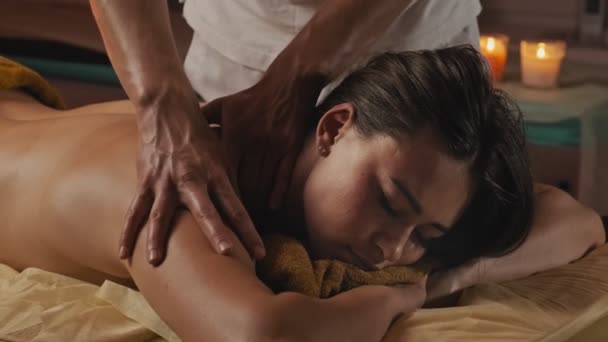 Mujer disfrutando de masajes corporales en el club de spa. Morena mujer acostada con los ojos cerrados . — Vídeos de Stock