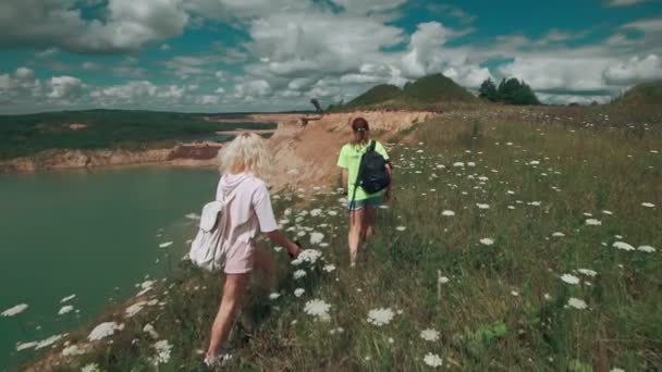 Jolies filles voyageant. Les femelles marchent à la carrière avec le lac. Concept de voyage — Video