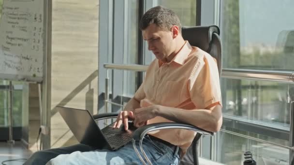 Προγραμματιστής του Office σοβαρά κοιτάζει την οθόνη του φορητού υπολογιστή. Ελεύθερος επαγγελματίας — Αρχείο Βίντεο