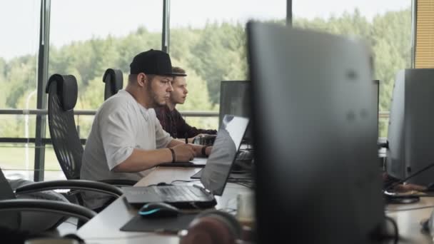 Jonge man werken met laptop op zoek in de monitor. Man in Cap met behulp van computer — Stockvideo