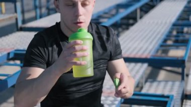 Genç sporcu yeşil spor şişesinden su içiyor. Yavaş çekimde egzersiz sonrası terleme ferahlatıcı içecek olan susuz atlet