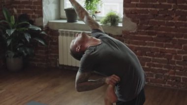 Genç adam yoga ve yavaş hareket tuğla duvar ile stüdyoda germe. Sağlıklı yaşam tarzı kavramı. Görünümü kapat