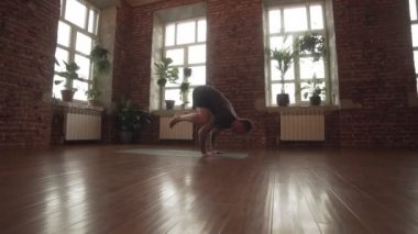 Genç adam asana yapıyor. El ayakta poz. Şehir stüdyosunda Yogi ana egzersiz. Pencerelerin yanında kapalı alanda yoga yapan adam. Sağlıklı yaşam tarzı kavramı