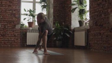 Şehir stüdyosunda siyah paspas üzerinde Yogi ana egzersiz. Pencerelerin yanında kapalı alanda yoga yapan adam. Genç adam yavaş çekimde asana yapıyor. Sağlıklı yaşam tarzı kavramı