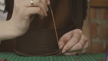 İğne ve dizeleri ile deri ustası dikiş. Profesyonel kadın skinner atölyede hakiki deri ile çalışıyor. El yapımı ve deri işçi konsepti.