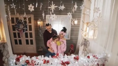 Kızı verandada sarılma ile genç aile, konuşma ve yavaş hareket Noel akşamı sıcak çikolata zevk. Tam uzunlukta çekim