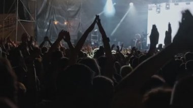 Geceleri rock konserinde insanlar ellerini havaya kaldırarak eğleniyorlar. Konserde dans eden kalabalığın görüntüleri. Heyecanlı hayranlarıkalabalık popüler grup alkışlıyor