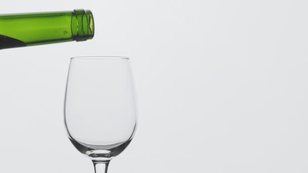 Pomalý pohyb nalijte červené víno z láhve do mixu s prostorem pro kopírování vpravo. Zblízka na červené víno tvoří krásnou vlnu ve skle. Víno ve skle na bílém pozadí.