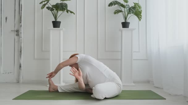 Красиві вагітні роблять йогу на підлозі. Молода вагітна жінка розтягується — стокове відео