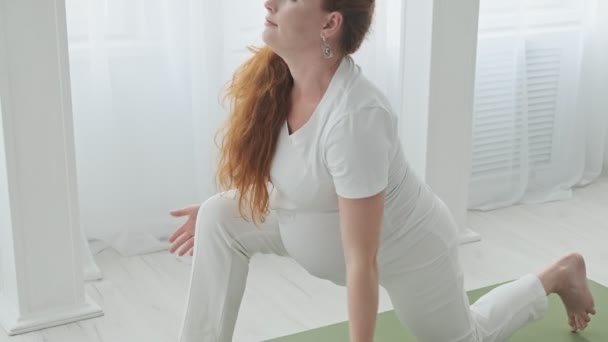 Jeune rousse femme enceinte faisant étirement à la maison au ralenti. 4k, UHD — Video