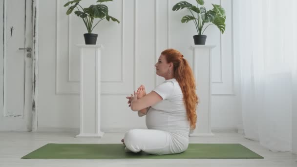 Vacker gravid gör yoga på golvet hemma. Aktiv rödhårig gravid kvinna — Stockvideo