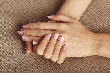 Young Female Palm on beige background. Beautiful Glamour Manicure. French Style. Nail polish. Care about Hands and Nails, clean Skin clipart