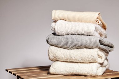 Tahta Masaya Sıcak Moda Kazakları Yığını. Sonbahar ve Kış Yünü Kıyafetleri. Örgü süveter ya da ceket. Yumuşak Renkler. Koşullandırma ve Yıkama