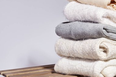 Tahta Masaya Sıcak Moda Kazakları Yığını. Sonbahar ve Kış Yünü Kıyafetleri. Örgü süveter ya da ceket. Yumuşak Renkler. Koşullandırma ve Yıkama