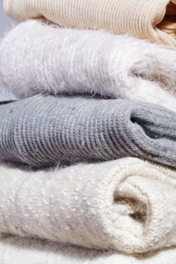 Tahta Masaya Sıcak Moda Kazakları Yığını. Sonbahar ve Kış Yünü Kıyafetleri. Örgü süveter ya da ceket. Yumuşak Renkler. Koşullandırma ve Yıkama