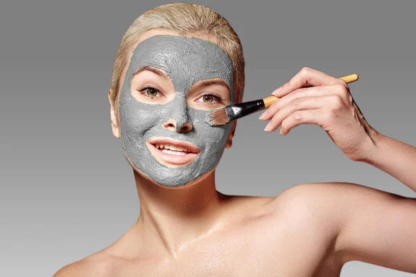 Wanita cantik menerapkan masker wajah tanah liat. Perawatan kecantikan. Spa Girl Apply Clay Facial mask with Beauty Brush — Stok Foto