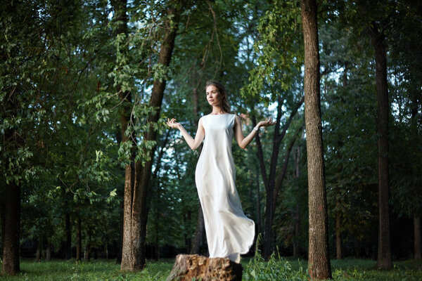 Beautiful Woman Posing like Goddess in White Long Dress at Nature. Boho Style, Soul Calm, Wellness. Freedom and Relaxing