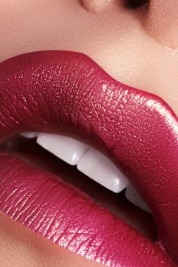 Makro yakın plan göz kamaştırıcı, parlak kırmızı dudaklar altın parıltısıyla süslenmiş. Makro kadın yüzü parçası. Seksi dudak makyajı, lüks bir yüz.