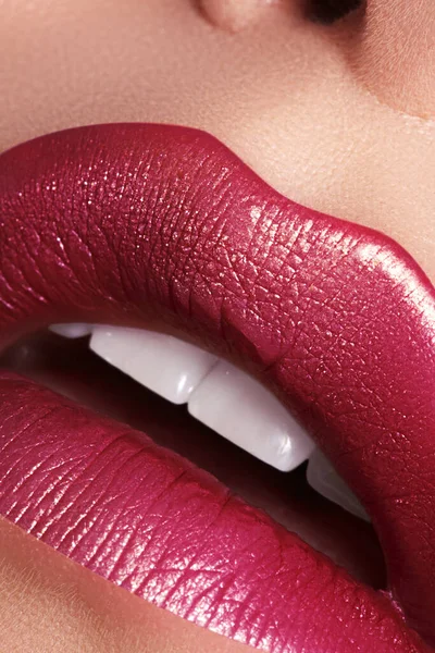 Makro yakın plan göz kamaştırıcı, parlak kırmızı dudaklar altın parıltısıyla süslenmiş. Makro kadın yüzü parçası. Seksi dudak makyajı, lüks bir yüz.