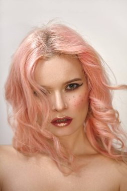 Kıvırcık saçlı güzel bir kadın. Yüzünde seksi bir makyajla yumuşak kız tarzı, kırmızı dudaklar ve pembe allık. Moda Rüzgarı