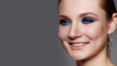 Closeup Macro of Beautiful Smiling Woman Face with Blue Eyes Make-up. Fashion Celebrate Makeup, Glowy Clean Skin, perfect Shapes of Brows. Shiny Simmer and Rouge.