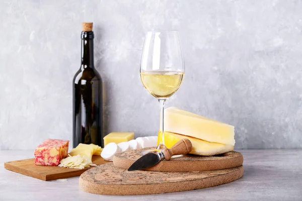 Variety of goat and cow milk cheese served with white wine over Portuguese cork boards and grey Background. Copy space