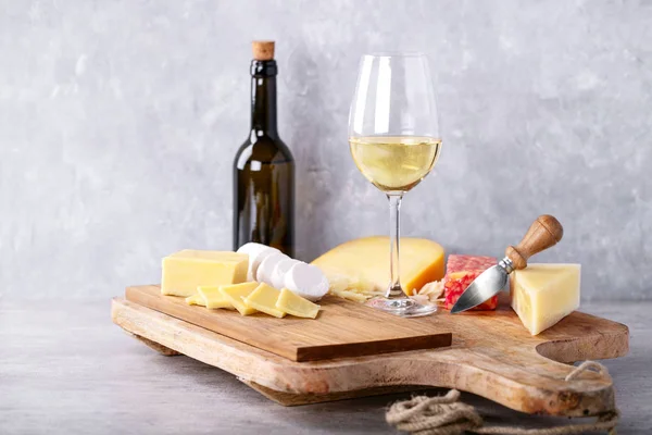 Variety of goat and cow milk cheese served with white wine over Portuguese cork boards and grey Background