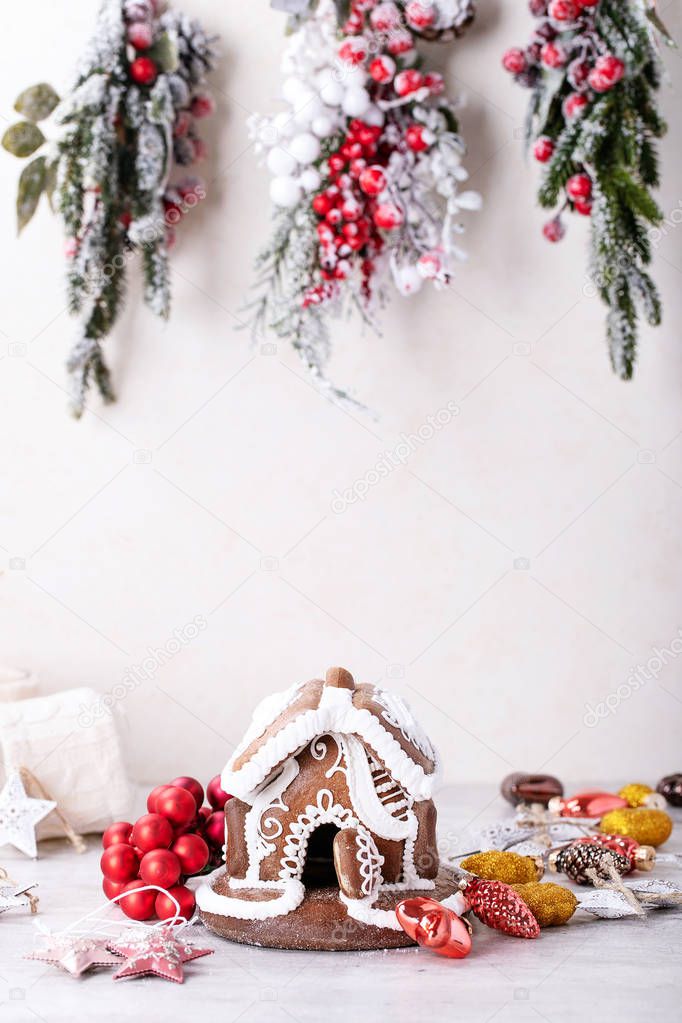 Home made Gingerbread house with white icing decorated with deer shaped cookies and traditional Christmas decorations