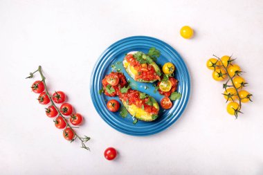 Bir avokado içinde pişmiş ve domates sosu, zeytin yağı ile hizmet yumurta ve taze organik Salantro sarı ve kırmızı içinde yarım dilimlenmiş domates ile dekore edilmiştir. Üstten görünüm