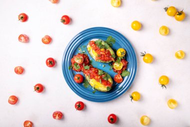 Bir avokado içinde pişmiş ve domates sosu, zeytin yağı ile hizmet yumurta ve taze organik Salantro sarı ve kırmızı içinde yarım dilimlenmiş domates ile dekore edilmiştir. Üstten görünüm