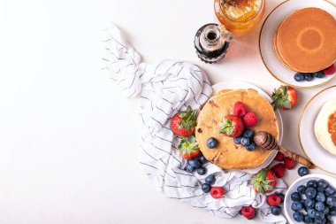 Yaban mersinli krep beyaz arka plan üzerinde çilek, böğürtlen, ahududu, bal ve akçaağaç şurubu ile görev yaptı. Üstten görünüm. Kopya alanı